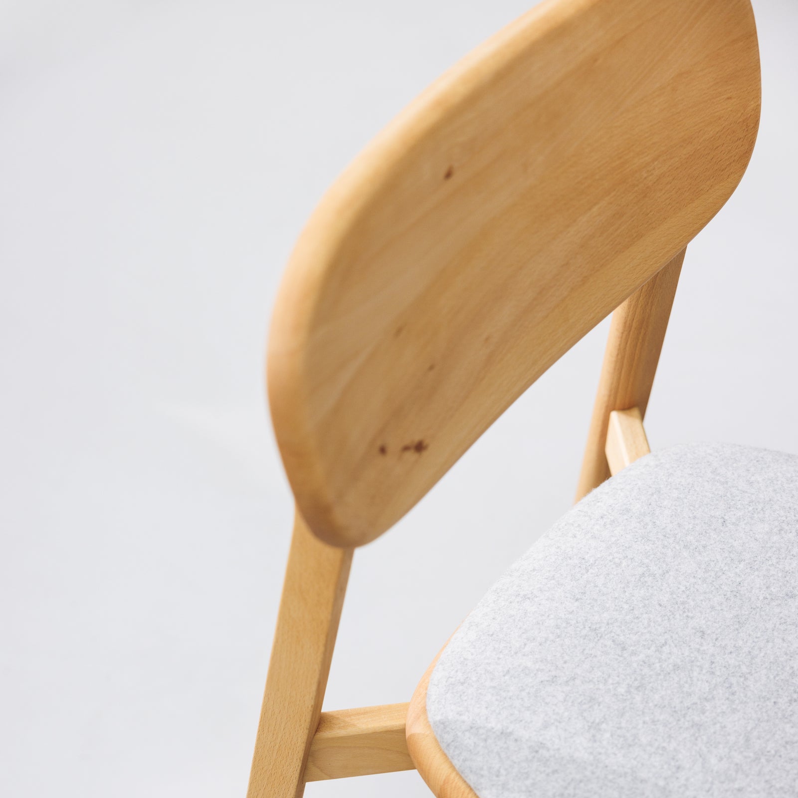 Designer-Stuhl aus Massivholz mit geschwungener Rückenlehne und grauem Sitzpolster