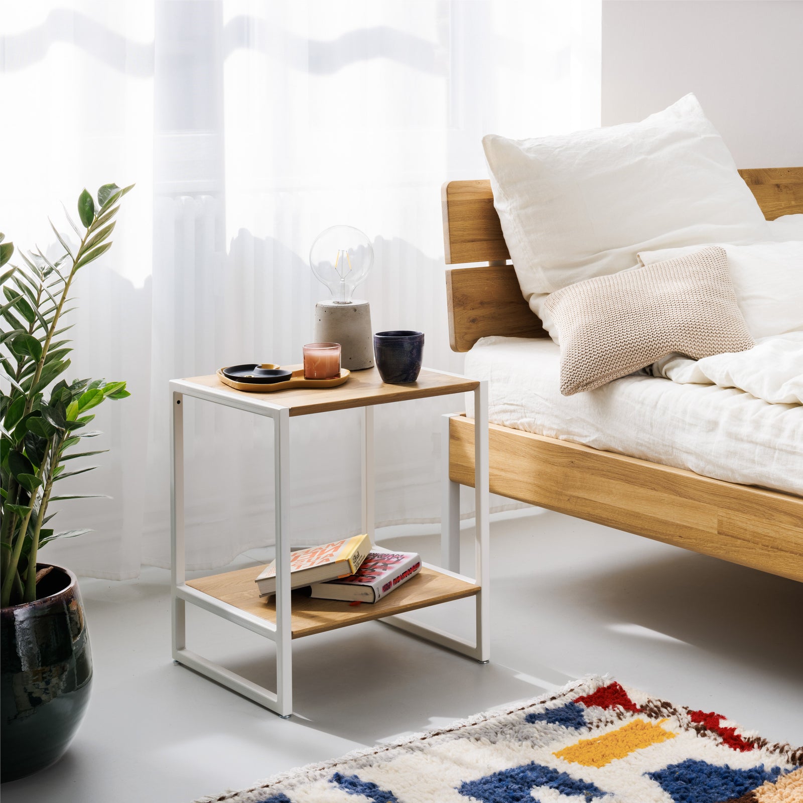 Schlichter Nachttisch neben minimalistischen Bett aus massiver Eiche mit Metallakzenten und nachhaltiger Bettwäsche