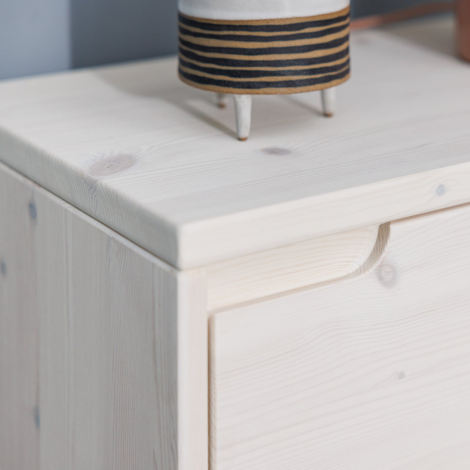 Hochwertiges Lowboard aus massivem Holz mit weiß lasierter Oberfläche und eingefrästem Griff in puristischem Design